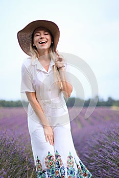 Young girl wearing hat and white dress standing on lavender field, Provans.