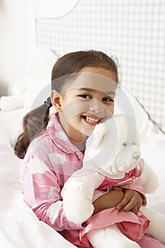 Young Girl Wearing Pajamas In Bed With Cuddly Toy