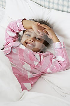 Young Girl Wearing Pajamas Lying In Bed