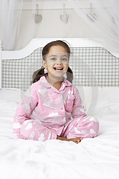 Young Girl Wearing Pajamas Sitting On Bed