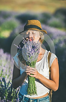 Young girl wearing straw hat enjoying bouquet of lavender flowers