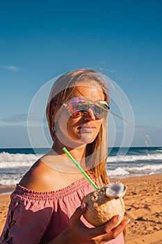 Young girl wearing sunglasses walking down the beach
