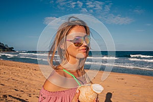 Young girl wearing sunglasses walking down the beach