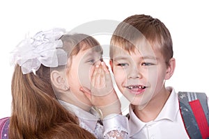 Young girl whispers in boy`s ear.