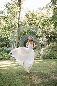 Young girl in a white dress in the meadow. Woman in a beautiful long dress posing in the garden. Stunning bride in a wedding dress