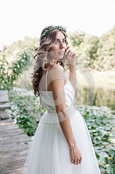 Young girl in a white dress in the meadow. Woman in a beautiful long dress posing in the garden. Stunning bride in a wedding dress