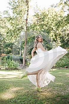 Young girl in a white dress in the meadow. Woman in a beautiful long dress posing in the garden. Stunning bride in a wedding dress