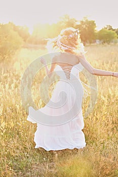 Young girl in a white dress in the meadow. Woman in a beautiful long dress posing in the garden. Stunning bride in a wedding dress