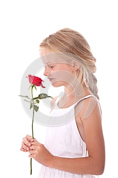 Young girl in white dress smelling a red rose