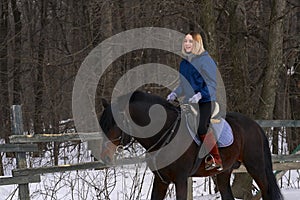 A young girl with white hair learns to ride a horse. The girl recently started to practice equestrianism. The girl is afraid of ri