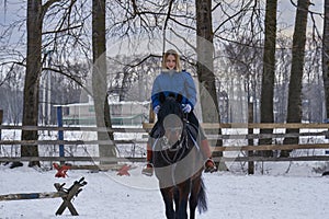 A young girl with white hair learns to ride a horse. The girl recently started to practice equestrianism. The girl is afraid of ri