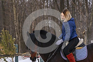 A young girl with white hair learns to ride a horse. The girl recently started to practice equestrianism. The girl is afraid of ri