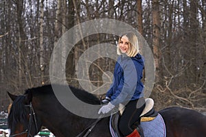 A young girl with white hair learns to ride a horse. The girl recently started to practice equestrianism. The girl is afraid of ri