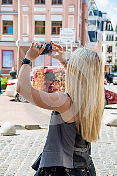 Young girl with white hair photographs a cityscape on a phone