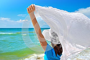 Young girl in a white hat on the sea beach. Clean, sandy beach against the blue sea