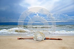 Young girl in a white hat on the sea beach. Clean, sandy beach against the blue sea