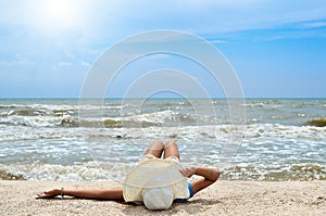 Young girl in a white hat on the sea beach. Clean, sandy beach against the blue sea