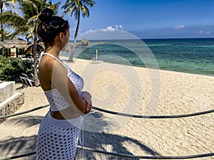 Young girl in white sexy clothes contemplating the horizon of a paradisiacal beach photo