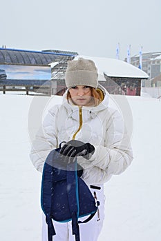 Young girl in white ski suit with blue backpack