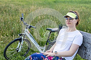 A young girl in a white T-shirt by bicycle looking somewhere