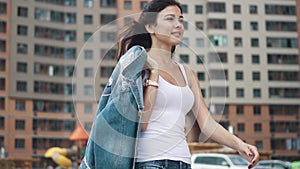 A young girl in a white t-shirt and jeans is between the high modern residential houses