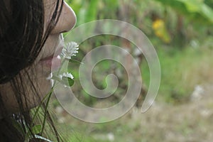 Young girl with a wild grass flower on her lip in the field.
