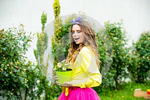Young girl winking and planting flowers in pot. Working with plants. Summer farm. Spring village country. Cute girl with