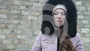 Young girl in winter clothes chews the cud