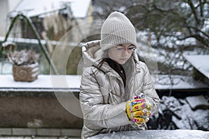Young girl in winter clothes with gloves and hat on the street