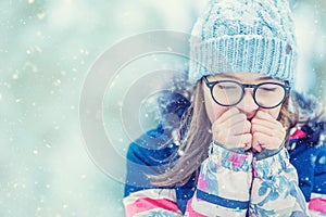 Young girl in winter clothes warming her cold hands