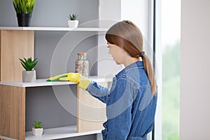 Young girl wiping shelf and folders, office cleaning concept