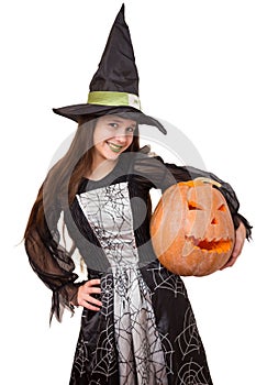 Young girl in witch costume with big pumpkin in hand