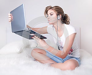 Young girl witn silver laptop and skype headset