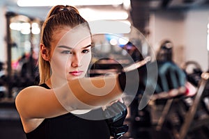 Young girl or woman with gloves, doing exercise in a gym.