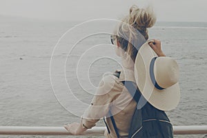 Young girl woman holding her straw hat watching on the ocean. Tr