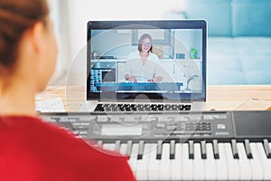 Giovane una donna insegna sul giocare pianoforte l'insegnante sul conferenza computer portatile. l'insegnante sul schermo spiega 