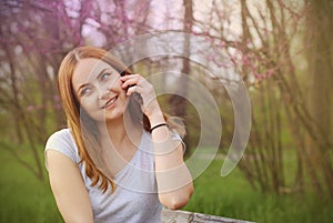 Young Girl Women Talking on a Mobile Phone Green Summer Garden. A Blonde Woman Smiling till Talking on a Smartphone