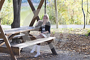 The young girl at a wooden table at the lake