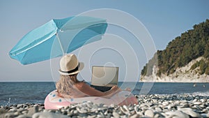 Young girl working on laptop outdoors in summer vacation