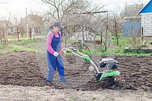 Young girl working in a spring garden with a cultivator