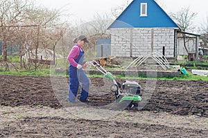 Young girl working in a spring garden with a cultivator