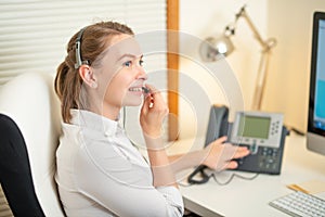 A young girl works in a call center. For a workplace with a telephone. A microphone with a microphone. Support service. Help desk