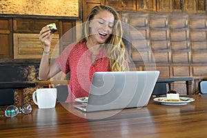 The young girl works at the computer and cake, food at the computer, a bad habit eats.