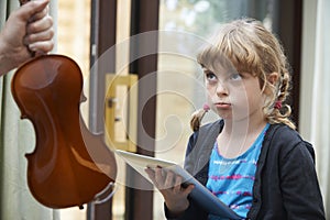 Young Girl Would Rather Play On Digital Tablet Than Practise Violin photo