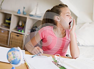 Young Girl Yawning, Doing Her Homework