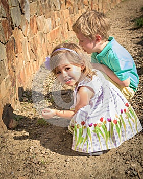 A young girl of 3 years and a boy of 5 years rest in a rock garden. photo