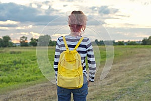 Young girl with yellow backpack, back, , evening sunset sky