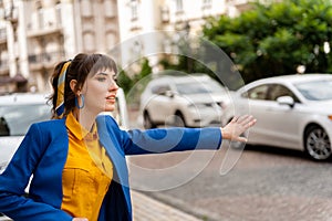 Young girl in a yellow shirt and blue jacket. Bright beautiful woman stops and causes a taxi raising her hand