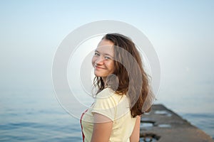 Young girl in yellow t-shirt on the sea and blue sky background, summertime, travelling, female portrait concepts