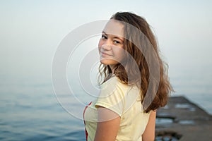 Young girl in yellow t-shirt on the sea and blue sky background, summertime, travelling, female portrait concepts